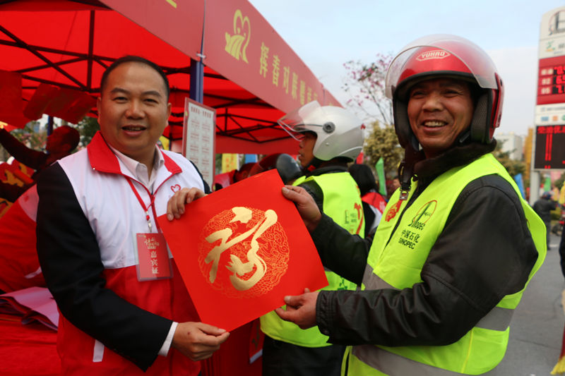 志願者為騎摩托車返鄉務工人員贈送“手寫”春聯