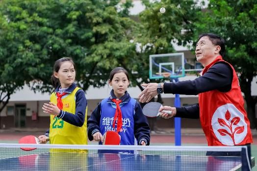 维他奶（东莞）有限公司总经理刘勇和东莞市常平镇第一小学孩子们一起打乒乓球。（受访者供图）