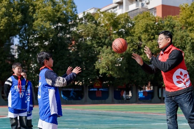 维他奶（武汉）有限公司总经理董剑涛和阳逻街武湖小学学生们一起打篮球。（受访者供图）